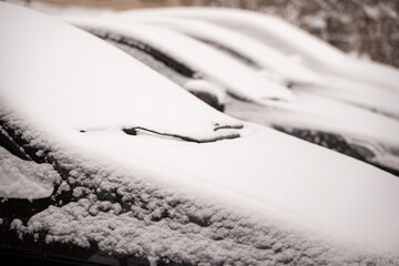 Parking with Snow-covered cars. Car window and wipers in the snow. Traffic safety. Selective focus