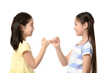 Cute Asian sisters making pinky promise on white background
