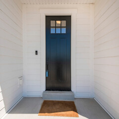 Fototapeta premium Square frame Exterior of a house with a view of black wooden door with glass panel and an enginered wood sidings