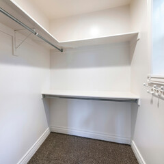 Square frame Walk in closet with dark brown carpet flooring and wall mounted shelves and hooks