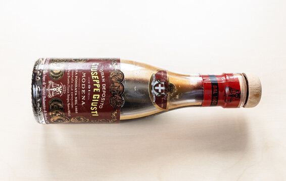 MOSCOW, RUSSIA - JUNE 10, 2021: lying used glass bottle of aged Giuseppe Giusti Aceto Balsamico di Modena on pale board. Giusti family is Italy's oldest Balsamic Vinegar producer since 1605