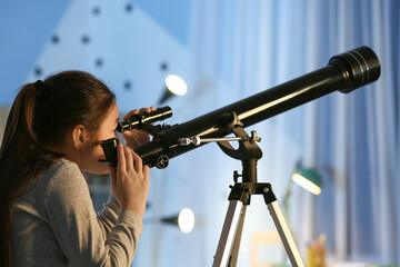 Cute little girl with telescope looking at stars in evening