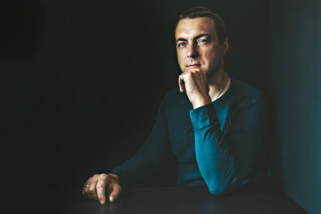 Portrait of a young man in a blue shirt in a dark key