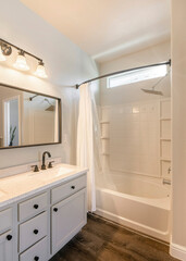 Vertical Open white masters bathroom with double vanity sink and bathtub shower with white curtain