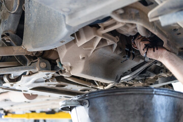 mechanic drains old engine oil from lifted car