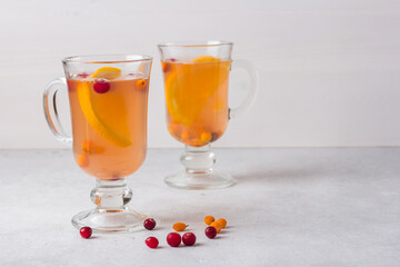 Two glasses of healthy fruit vitamin tea with orange, buckthorn and cranberries. Copy space.