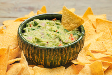 Bowl with tasty guacamole and nachos on table, closeup