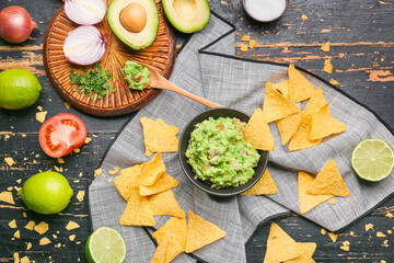 Composition with tasty guacamole and nachos on dark wooden background