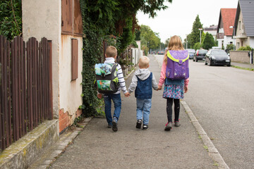 Obraz premium Thre children walking to school. First school day.