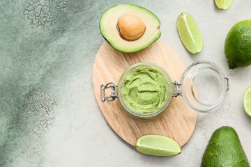 Glass jar with tasty guacamole and lime on color background