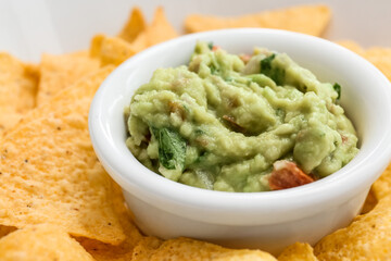 Bowl with tasty guacamole and nachos, closeup
