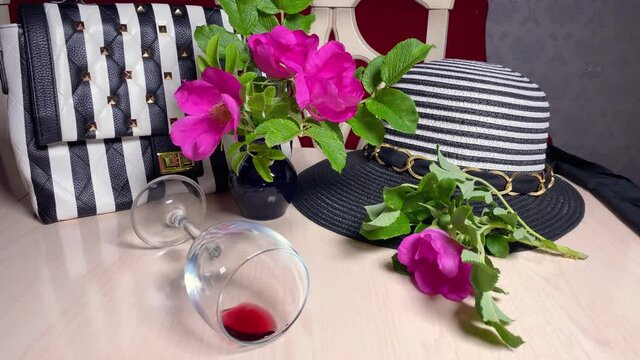 Striped hat, black and white purse with stripes on table. Wineglass with red wine. Modern fashion style