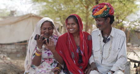 South Asian family in traditional Indian clothing using a phone together