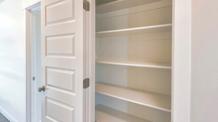 Pano Linen closet of house with wide shelves for storing organization and white door