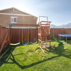 Square frame Backyard playground with wooden fence and a view of a mountain range and neighbor's...