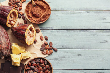 Composition with fresh cocoa fruits, beans, powder, butter and chocolate on color wooden background