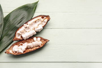 Fresh cocoa fruit and green leaves on color wooden background