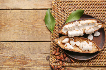 Plate with fresh cocoa fruit on wooden background