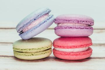 Multicolored macarons on a table and white wall background