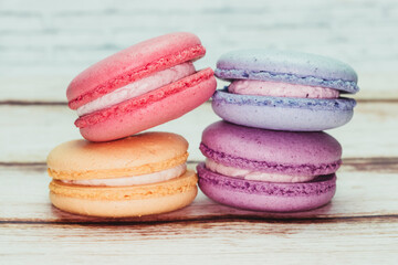 Multicolored macarons on a table and white wall background