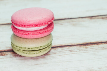 Multicolored macarons on a table and white wall background