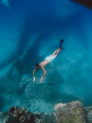 Boy snorkels next to a ship wreck submerged in the ocean