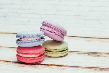 Multicolored macarons on a table and white wall background