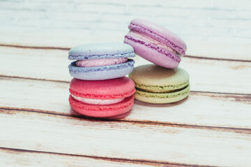 Multicolored macarons on a table and white wall background