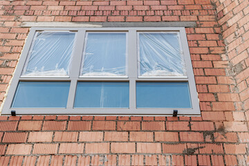 Installation of a window in a brick building. Industrial engineering. Darkening and installation of a window opening using polyurethane foam.