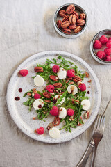 Summer salad with arugula, raspberries, mozzarella cheese and pecan nuts. Morning, breakfast, healthy food. Selective focus