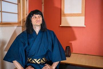 Traditional sliding paper doors in Japan with man in kimono costume and black hair sitting by...