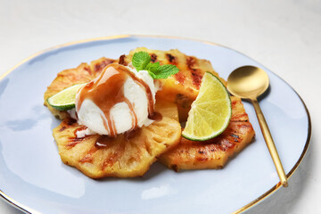 Plate with grilled pineapple slices and ice cream on light background, closeup