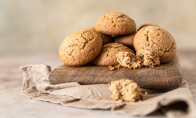 Oatmeal cookies on wooden cutting board, brown concrete background. Healthy snack or dessert.