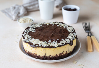 Delicious creamy cheesecake decorated with chocolate glaze and almond, light concrete background. No bake mousse dessert.