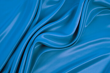 Beautiful elegant wavy blue satin silk luxury cloth fabric texture with monochrome background design. Copy space