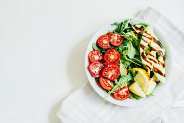 top view of tomato salad arugula avocado lemon in white plate on light background