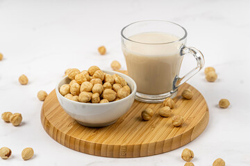 Hazelnut milk in a glass with nuts on a wooden table