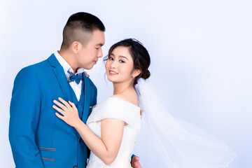 An Asian couple is photographed before the wedding in the happy groom and bride outfits against a white background. Pre Wedding