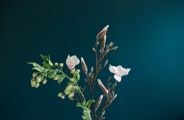 Beautiful faux magnolia plant against teal wall