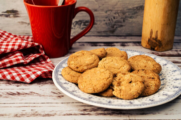 Classic country plate with raisin-seed oatmeal cookies, a red mug, and a napkin. Natural nutrition concept.