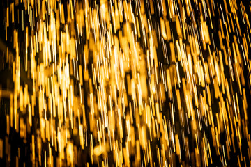 Abstract background of heavy rain shower with waterdrops in the golden rays of the sun in summer....