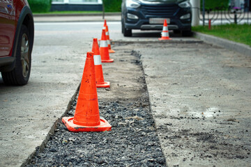 Roadwork, driveway repair, prepare for laying new asphalt. Damaged asphalt road surface repairing. Preparing for patch works. Repair pothole in asphalt pavement, road work warning cones.