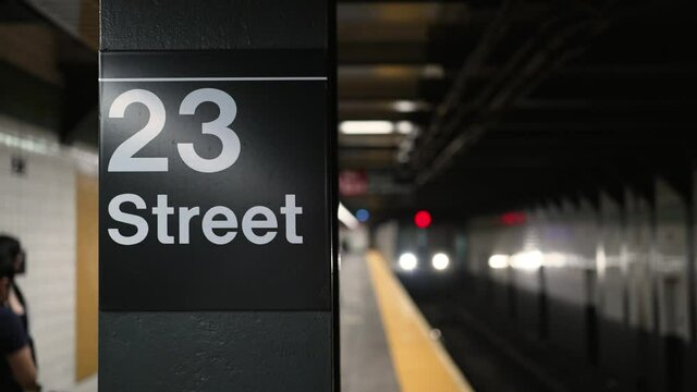 NEW YORK - Circa July, 2021 - The 23rd Street Station subway ID sign as a train approaches. Shot in slow motion.  	