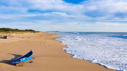 Immigrant and refugee dinghy boat stranded on the shore of a bautiful sand beach in south Spain....