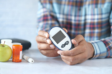 man's hand holding glucose meter while sited 