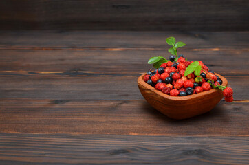 berries in a bowl on a wooden background with place for text