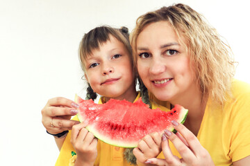 The concept of delicious summer snacks. A smiling mother and her eight-year-old daughter are eating a piece of ripe watermelon, a close-up, a place for text.