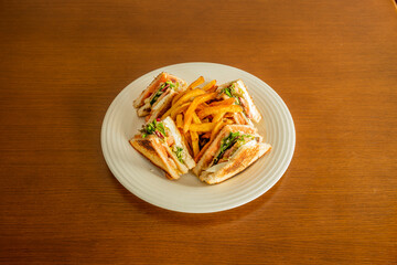 Club sandwich drizzled with mayonnaise sauce, fried chicken fillet, boiled egg, lettuce and tomato, fried bacon, crispy sliced bread and side of French fries.