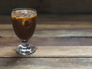 Wine glasses has iced latte coffee on empty old wood table top,dimly light,free space for text design.Concept of Relaxation in Coffee time.