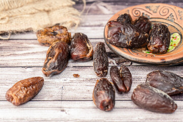 Normal view of fresh dates in a rustic plate on a wooden table. Concept of natural nutrition, organic fruits.
